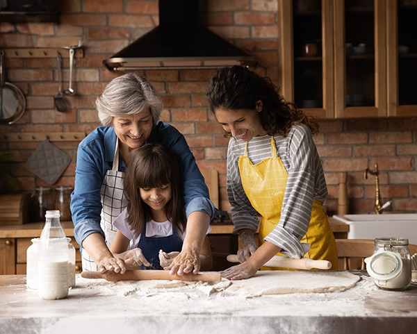 Multi-generational family rolling out pie crust.