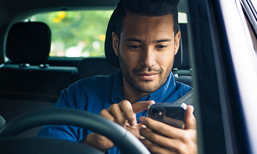 Man looking at his phone while sitting in his car