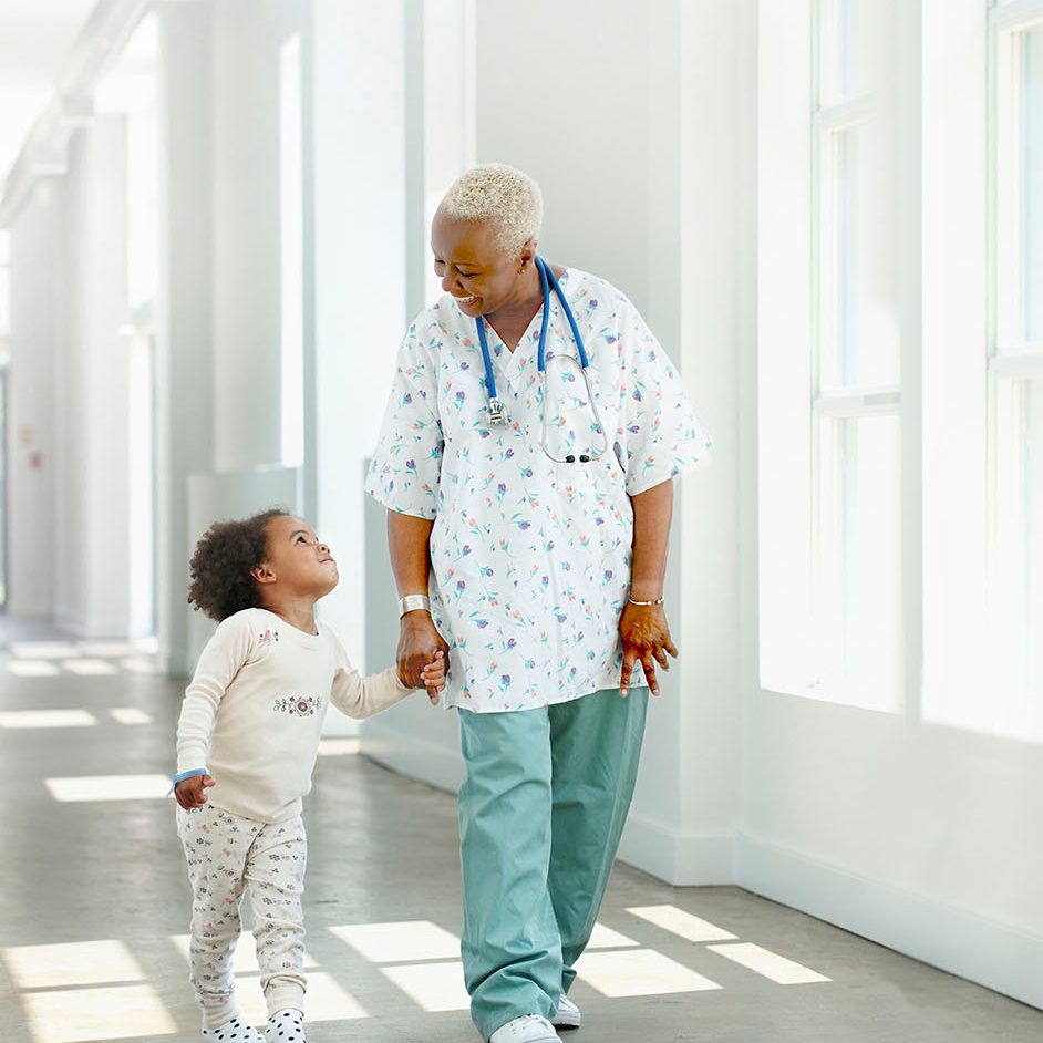 Nurse holding hands with a child in a hospital.