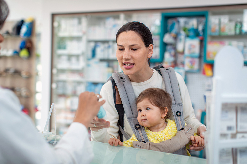 Mother with her baby checking out at a pharmacy.