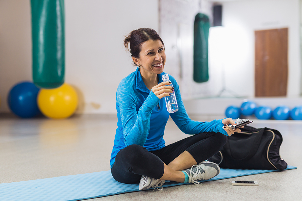 Woman getting a drink of water at the gym while earning Well OnTarget rewards.