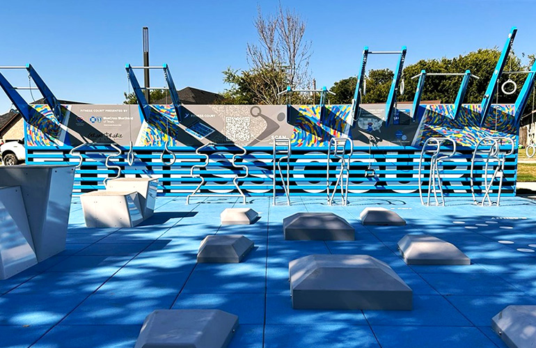 Excercise equipment on an outdoor court with trees and blue sky in the background