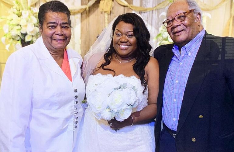 Woman in a white wedding dress holding flowers poses with grandparents