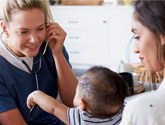 A doctor examining an infant in her mother's arms.