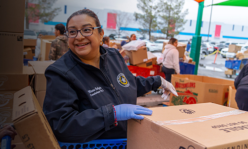 A woman sorts food boxes at a volunteer event